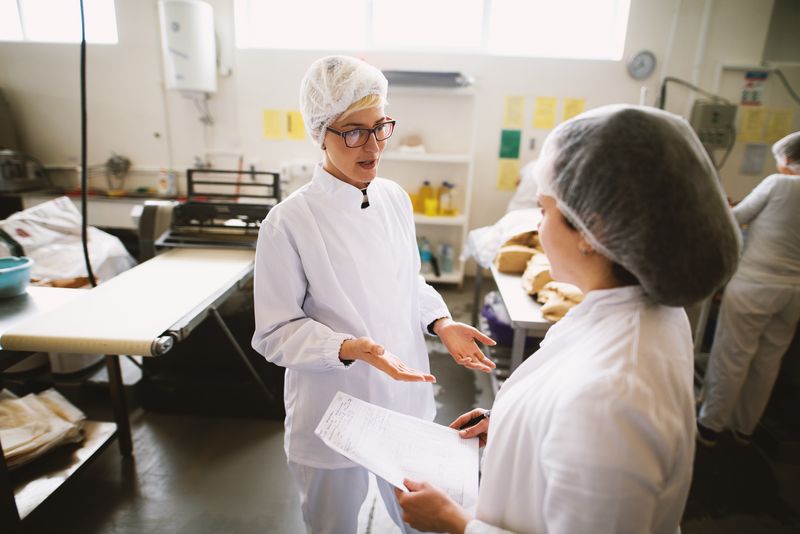 Two female workers in sterile cloths talking while standing in a